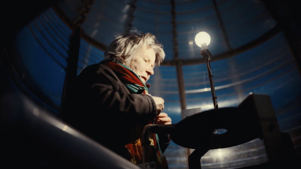 Person holds hands in low light with one lightbulb lit.